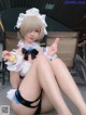 A woman in a maid outfit sitting on the ground with a popsicle.