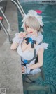 A woman in a maid outfit is sitting in a pool.