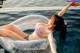 A woman in a bikini laying on an inflatable ring in a pool.