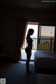 A woman standing in a hotel room looking out the window.