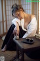 A woman sitting on the floor next to a table with a cup of tea.