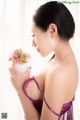 A woman in a purple lingerie holding a vase of flowers.