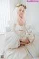 A woman in a wedding dress sitting on a bed.