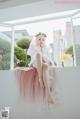 A woman in a wedding dress sitting on a window sill.