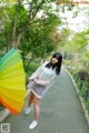 A woman in a white dress holding a colorful umbrella.