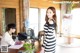 A woman in a black and white striped dress standing in front of a desk.