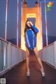 A woman in a blue sweatshirt and shorts posing on a bridge.