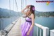 A woman in a purple dress standing on a bridge.