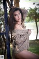 A woman leaning against a metal fence in a park.