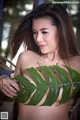 A woman holding a large green leaf in her hand.