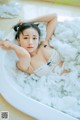 A woman laying in a bathtub filled with foam.