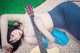 A woman laying on a blanket with a guitar.