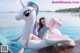 A woman sitting on an inflatable unicorn float in a pool.