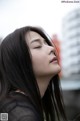 A woman with long black hair is looking up at the sky.