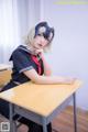 A woman in a school uniform sitting at a desk.