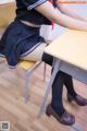 A woman in a school uniform sitting at a desk.