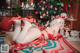 A woman in a red bikini laying on a blanket in front of a Christmas tree.