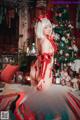 A woman in a red and white outfit posing in front of a Christmas tree.