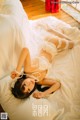 A woman laying on a bed in a white lingerie.