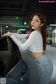 A woman leaning against a car in a parking garage.