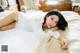 A woman laying on top of a bed in a white shirt.