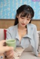 a woman sitting on a couch holding a cup of coffee