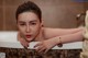 A woman leaning over the edge of a bathtub in a bathroom.