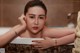 A woman sitting in a bathtub with her hand on her head.