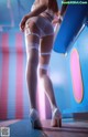 A woman in white stockings and high heels standing in front of a blue and pink wall.