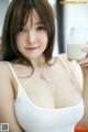 A woman in a white tank top holding a glass of milk.