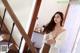 A woman in a white robe standing next to a staircase.