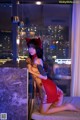 A woman in a red dress sitting on a bed.