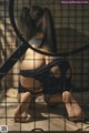 A woman sitting on the floor in front of a cage.