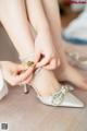 A woman is putting on her wedding shoes. 