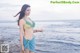 A woman in a bikini standing on a pier by the ocean.