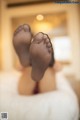 A woman laying on a bed with her feet up in the air.