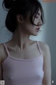 A woman in a pink tank top is looking away from the camera.