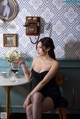 A woman in a black dress sitting at a table with a glass of wine.