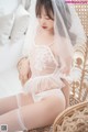 a woman in a white lingerie sitting on a wicker chair