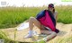 A woman sitting on a blanket in a field of tall grass.