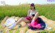 A woman sitting on a blanket in a field of tall grass.