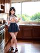 A woman in a school uniform standing in a kitchen.