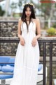 A woman in a white dress standing on a bridge.