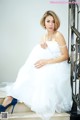 A woman in a white dress sitting on some steps.