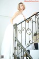 A woman in a wedding dress standing on a staircase.