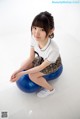 A young woman sitting on a blue ball on the floor.