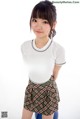 A woman in a white shirt and plaid skirt posing for a picture.