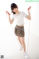 A woman in a white shirt and plaid skirt holding a skipping rope.