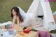 A woman in a wedding dress sitting on a picnic blanket.