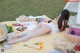 A woman laying on a picnic blanket in the grass.